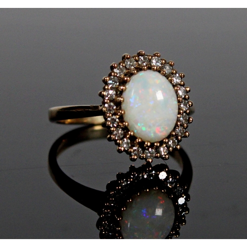 558 - 9ct gold and opal cluster ring, the oval opal wihin a halo of small white stones, size L/M, 2.9g.