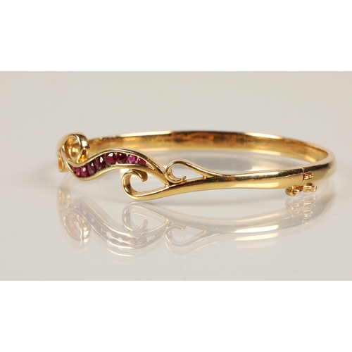 70 - 18ct yellow gold stiff bangle set with nine graduated rubies, 6cm diameter, 19.8 grams.