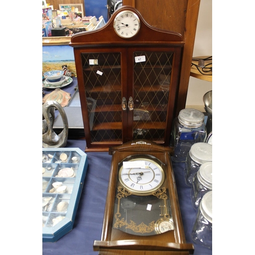 67 - Display case surmounted by a quartz clock and a wall clock.