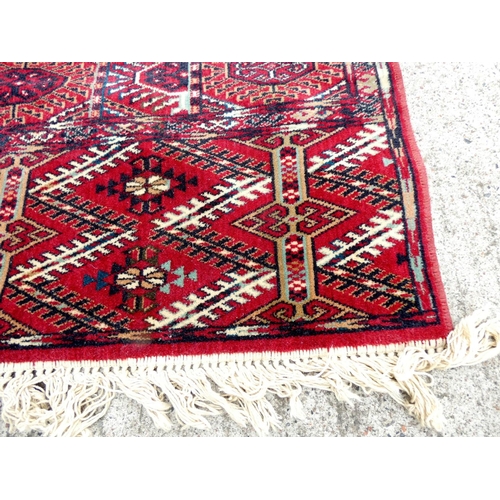 394 - Vintage machine made wool Bokhara rug having six rows of twelve medallions. 248cm x 344cm.