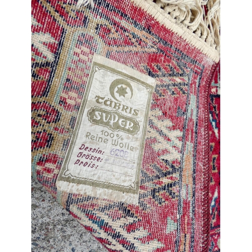 394 - Vintage machine made wool Bokhara rug having six rows of twelve medallions. 248cm x 344cm.