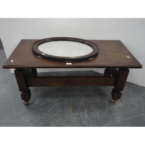 443 - Oak coffee table on castors and an oval wall mirror.  (2)