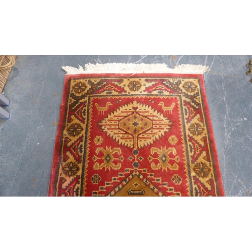 38 - Machine-made Persian design rug adorned with animals and geometric motifs, on red ground.