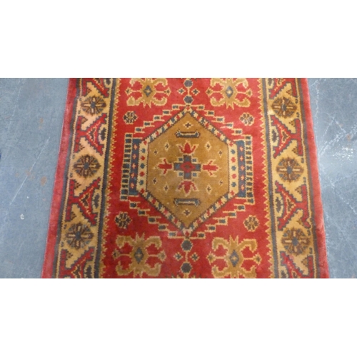 38 - Machine-made Persian design rug adorned with animals and geometric motifs, on red ground.