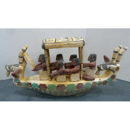 97 - Tribal figures on a boat, horned animal masks to the front and rear.