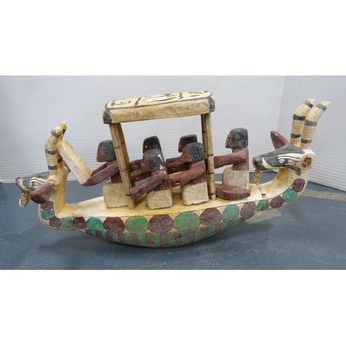 97 - Tribal figures on a boat, horned animal masks to the front and rear.