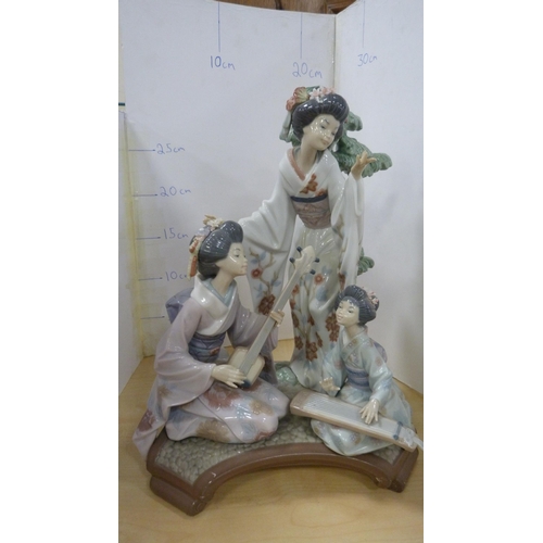 99 - Lladro group decorated by V Navarra, in the form of three Geisha playing instruments, with stand.