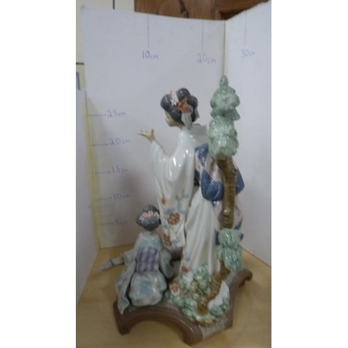 99 - Lladro group decorated by V Navarra, in the form of three Geisha playing instruments, with stand.