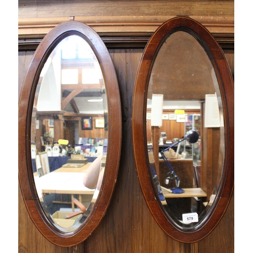 579 - Pair of mahogany oval wall mirrors, 58cm long.