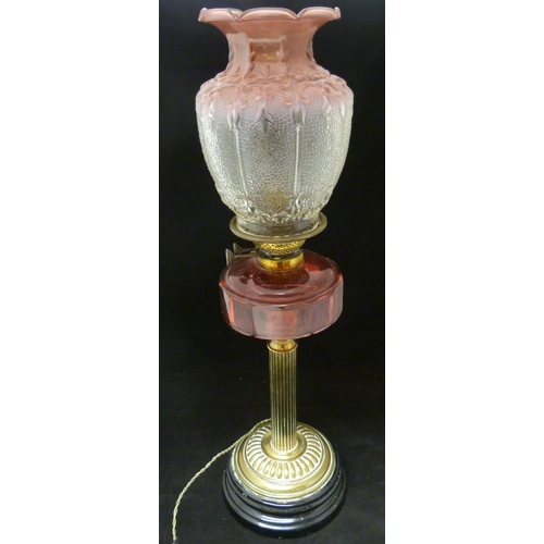 388 - Duplex oil lamp, c. early 20th century, with cranberry glass reservoir, above brass fluted cylindric... 