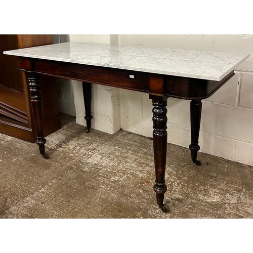 611 - Victorian side table with replacement marble top on casters, surface measures 58cm x 140cm, 76cm h