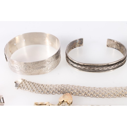 698 - Three silver bangles, a silver flex bracelet, two silver gate bracelets and a silver gilt gate brace... 