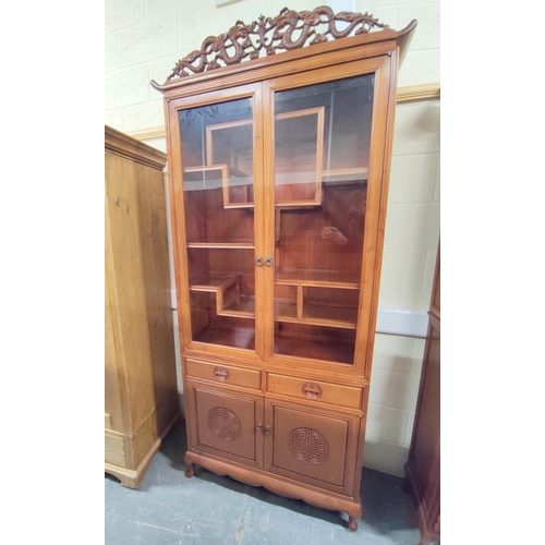 444 - 20th century Chinese rosewood display cabinet with carved dragon pediment, the twin glazed doors ope... 