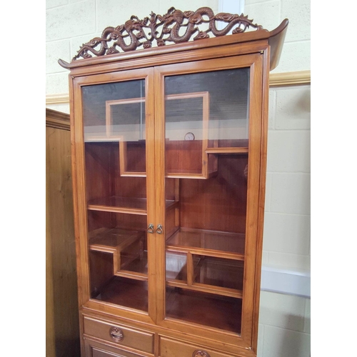 444 - 20th century Chinese rosewood display cabinet with carved dragon pediment, the twin glazed doors ope... 