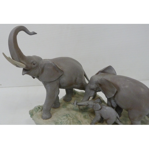 324 - Lladro matt glazed elephant group modelled as a male, female and baby elephant on naturalistic setti... 