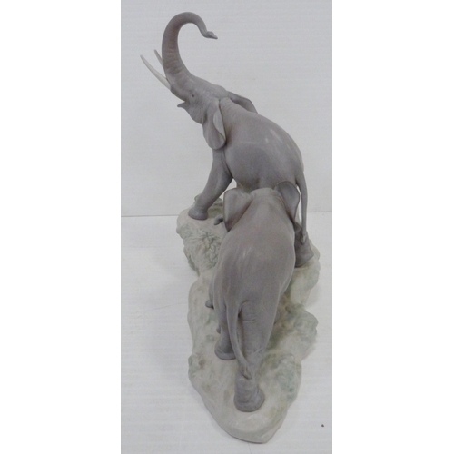 324 - Lladro matt glazed elephant group modelled as a male, female and baby elephant on naturalistic setti... 