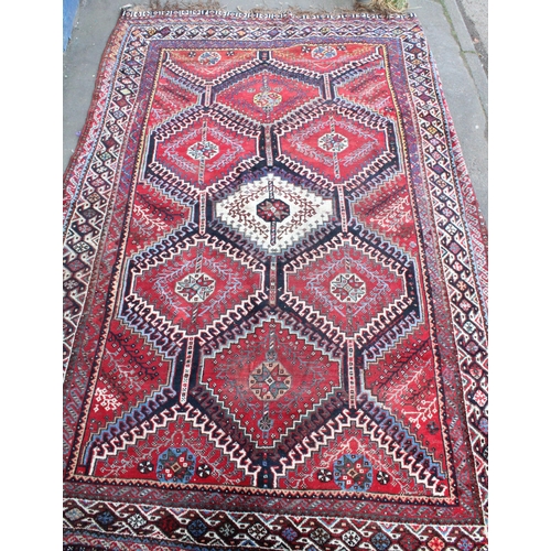 939 - Persian red ground carpet with repeating geometrical designs, 320cm x 215cm.