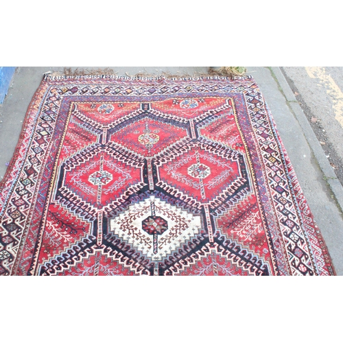 939 - Persian red ground carpet with repeating geometrical designs, 320cm x 215cm.