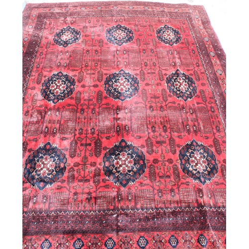 942 - Large Afghan tribal carpet with blue floral lozenges on a red ground, 370cm x 285cm.