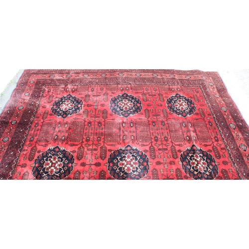 942 - Large Afghan tribal carpet with blue floral lozenges on a red ground, 370cm x 285cm.