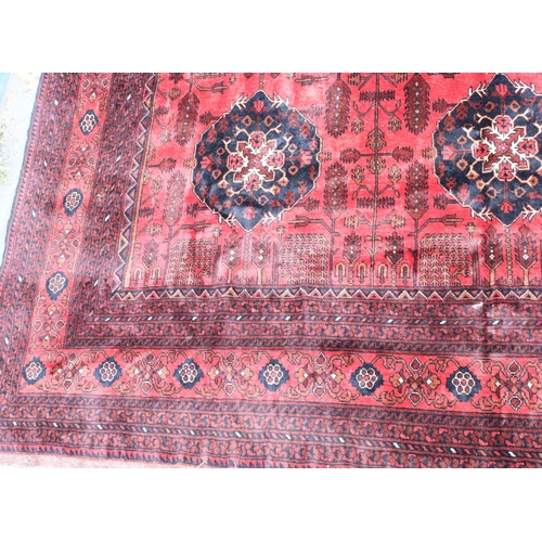 942 - Large Afghan tribal carpet with blue floral lozenges on a red ground, 370cm x 285cm.