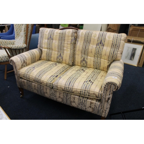 897 - Two seater upholstered sofa on tapered legs terminating in brass castors, W133cm.