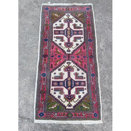 913 - Persian cream ground and red rug with geometric and birds decoration, 184cm x 94cm.