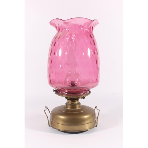 288 - Cranberry glass oil lamp, early 20thC, the dimpled large cranberry glass shade on a brass burner and... 