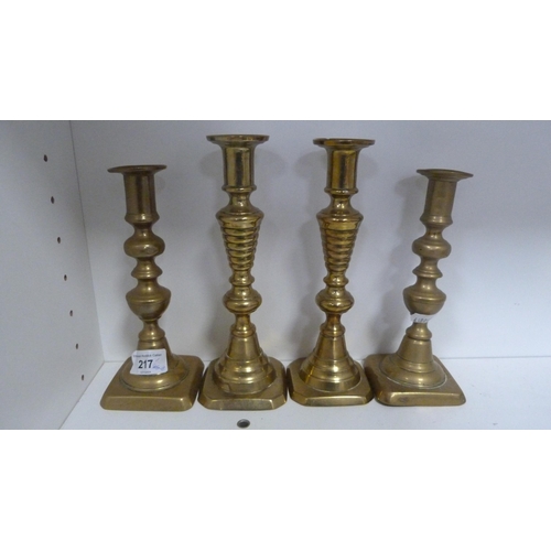 217 - Brassware to include two pairs of brass candlesticks, horse brasses, hip flask etc (one shelf).