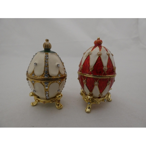 280 - Two contemporary decorative trinket boxes modelled as eggs by Atlas Editions, with stands, and anoth... 