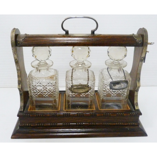 396 - Oak and silver plated three-bottle tantalus containing three matching cut glass decanters and stoppe... 