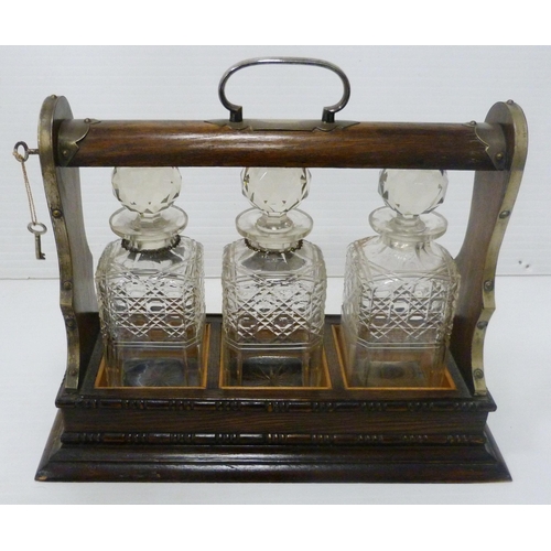 396 - Oak and silver plated three-bottle tantalus containing three matching cut glass decanters and stoppe... 