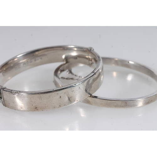 26 - Two half engraved silver bangles together with a silver cross pendant, gross 33g.