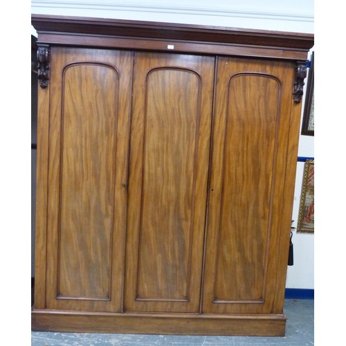 563 - Victorian mahogany three-door wardrobe, the moulded cornice above three doors, central pivot door, e... 