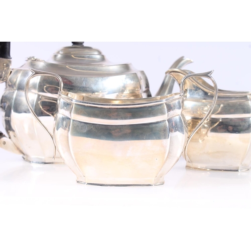 53 - Geo. V silver three piece tea set, the teapot with angular ebonized handle on a stepped oval body wi... 