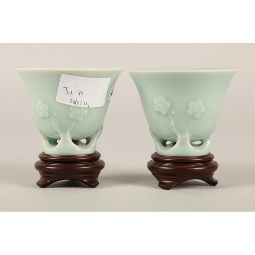 31A - Pair of Oriental celadon glaze ceramic cups on on wooden stands...