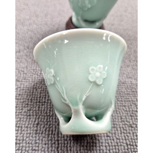 31A - Pair of Oriental celadon glaze ceramic cups on on wooden stands, each cup approx 6cm (not including ...