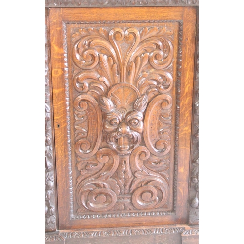 435 - Antique oak cabinet break front bookcase raised on plinth base, central door profusely carved with m... 