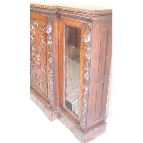 435 - Antique oak cabinet break front bookcase raised on plinth base, central door profusely carved with m... 