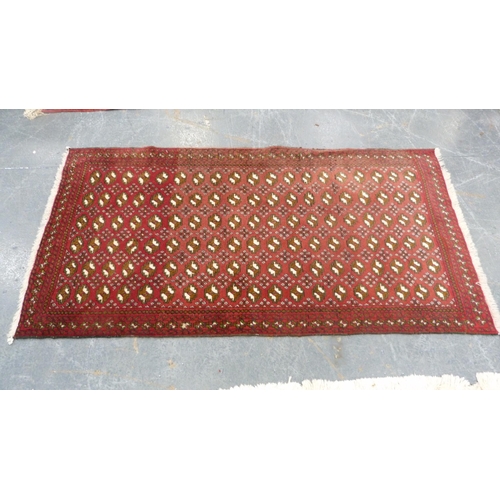 516 - Turkoman-style red ground rug decorated with six rows of guls, 193cm x 103cm.