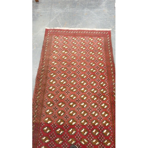 516 - Turkoman-style red ground rug decorated with six rows of guls, 193cm x 103cm.