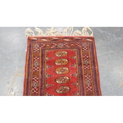 517 - Turkoman-style red ground rug with single row of guls, 150cm x 75cm.