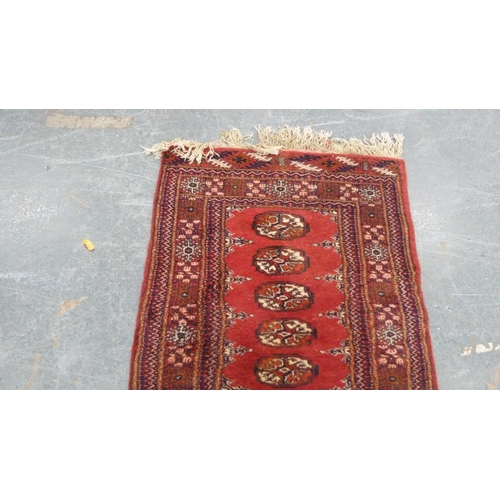 517 - Turkoman-style red ground rug with single row of guls, 150cm x 75cm.