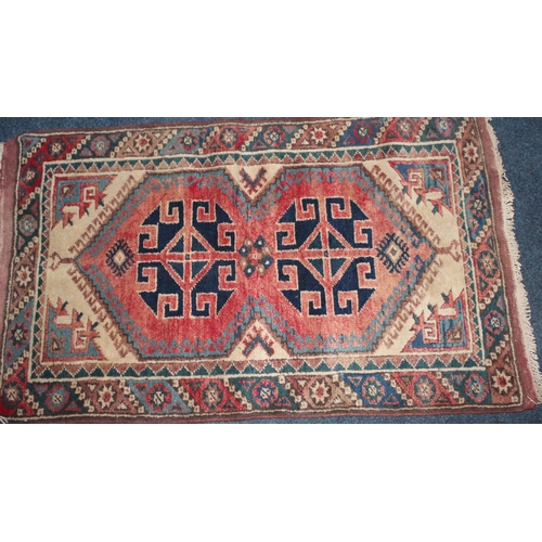 965 - Red ground rug with geometric decoration, 124cm x 72cm.