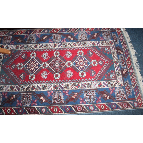 966 - Red ground rug with geometric pattern and decorative border, 197cm x 117cm.