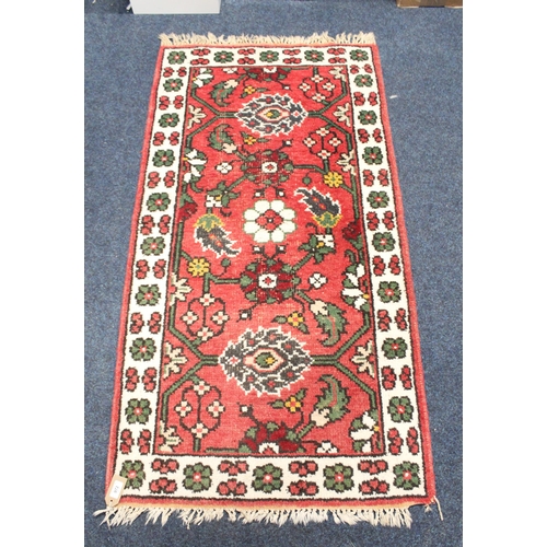 972 - Red ground fringed rug with geometric decoration, 80cm x 155cm.