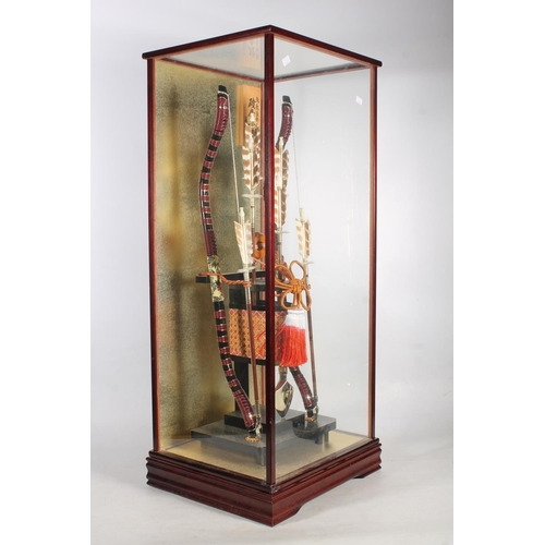 1 - Cased display of a pair of Japanese recurved short bows with arrows, 87cm high.