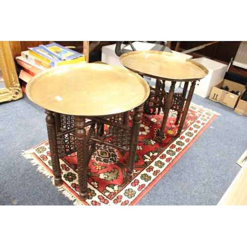 983 - Two Benares brass tray top folding tables on heavily carved bases.