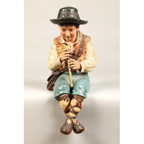 44 - Large seated pottery figure of a boy playing the flute, 52cm high.