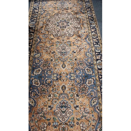 695 - Orange ground hall runner with floral field and multi border, 590cm long x 115cm wide.